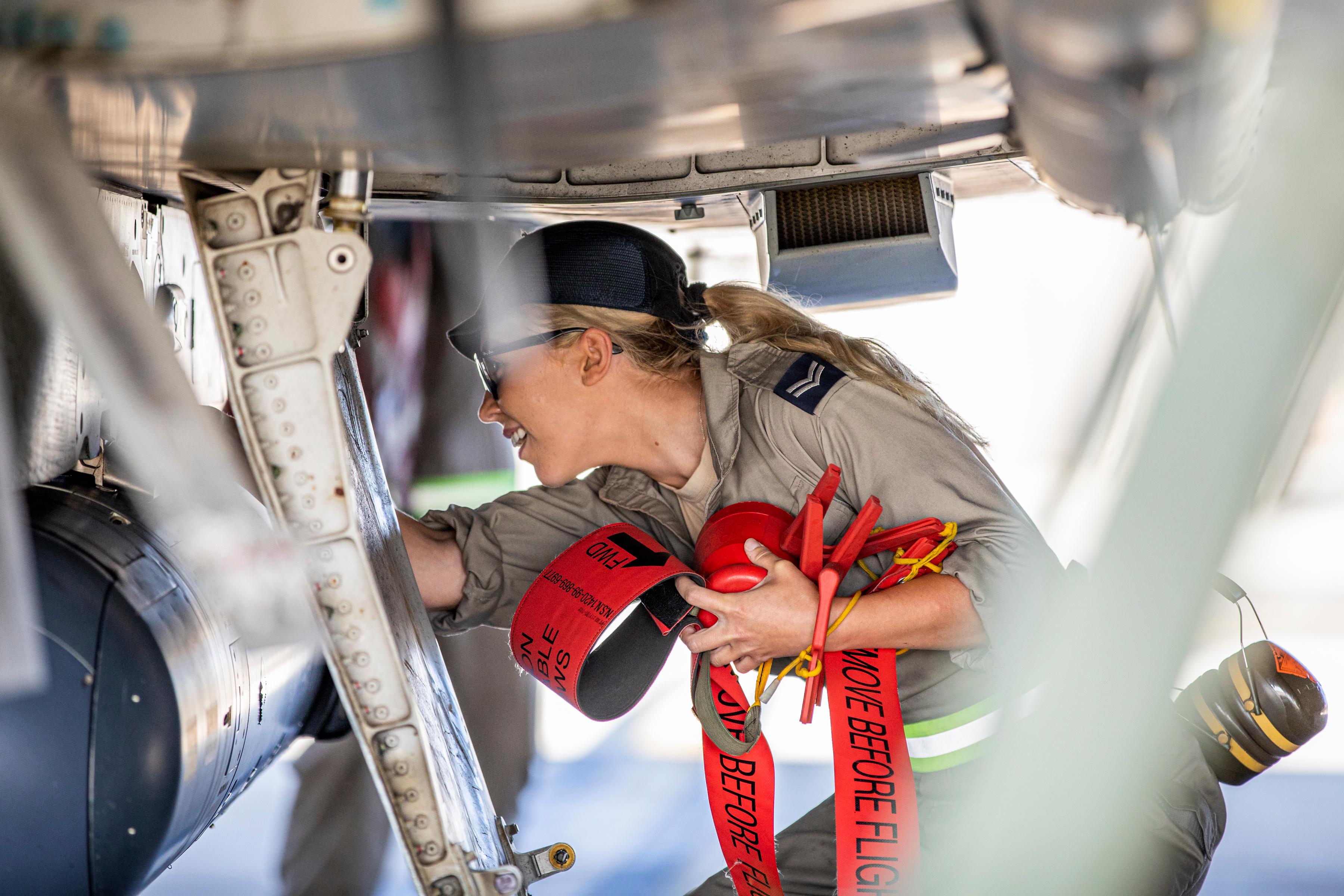 Female RAF engineer in uniform working on the undercarriage of a jet plane